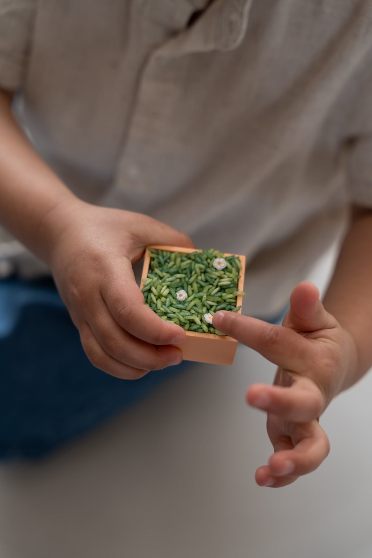 Kind houdt Grennn vierkant speelbakje met groene speelrijst