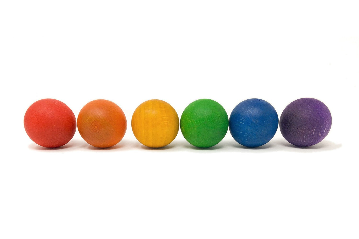 Zes houten Grapat ballen in regenboogkleuren op een rij