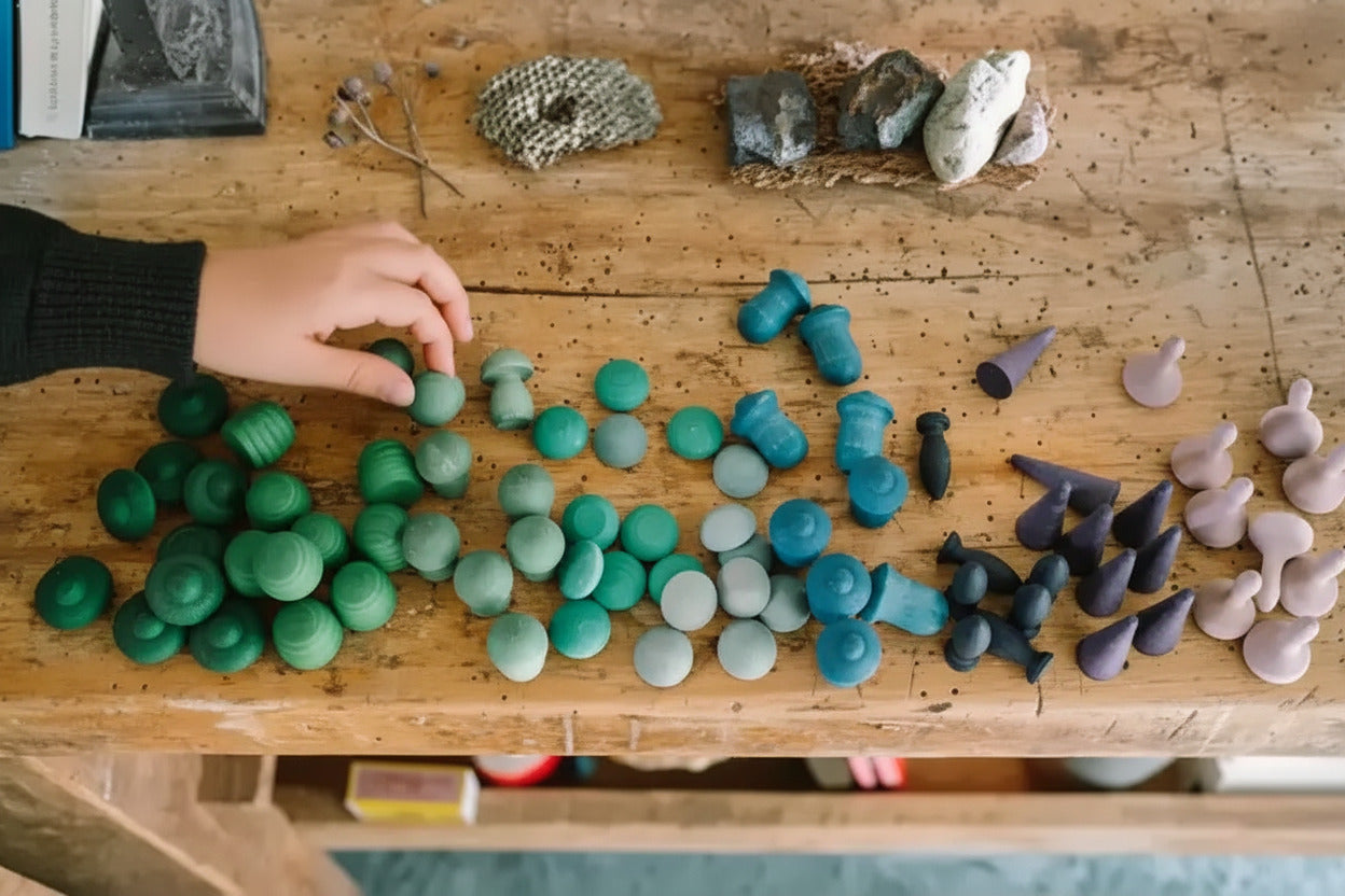 Handen sorteren blauwe en groene Mandala Mix onderdelen op een houten tafel