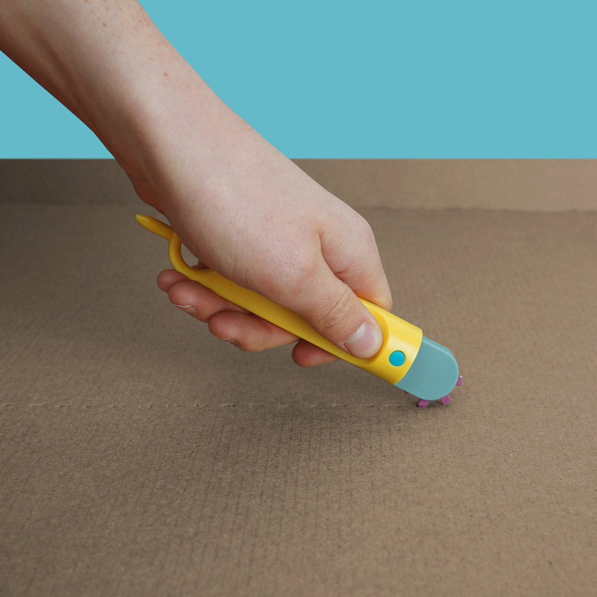 Hand rolt met gele Fold-Roller een vouwlijn in karton