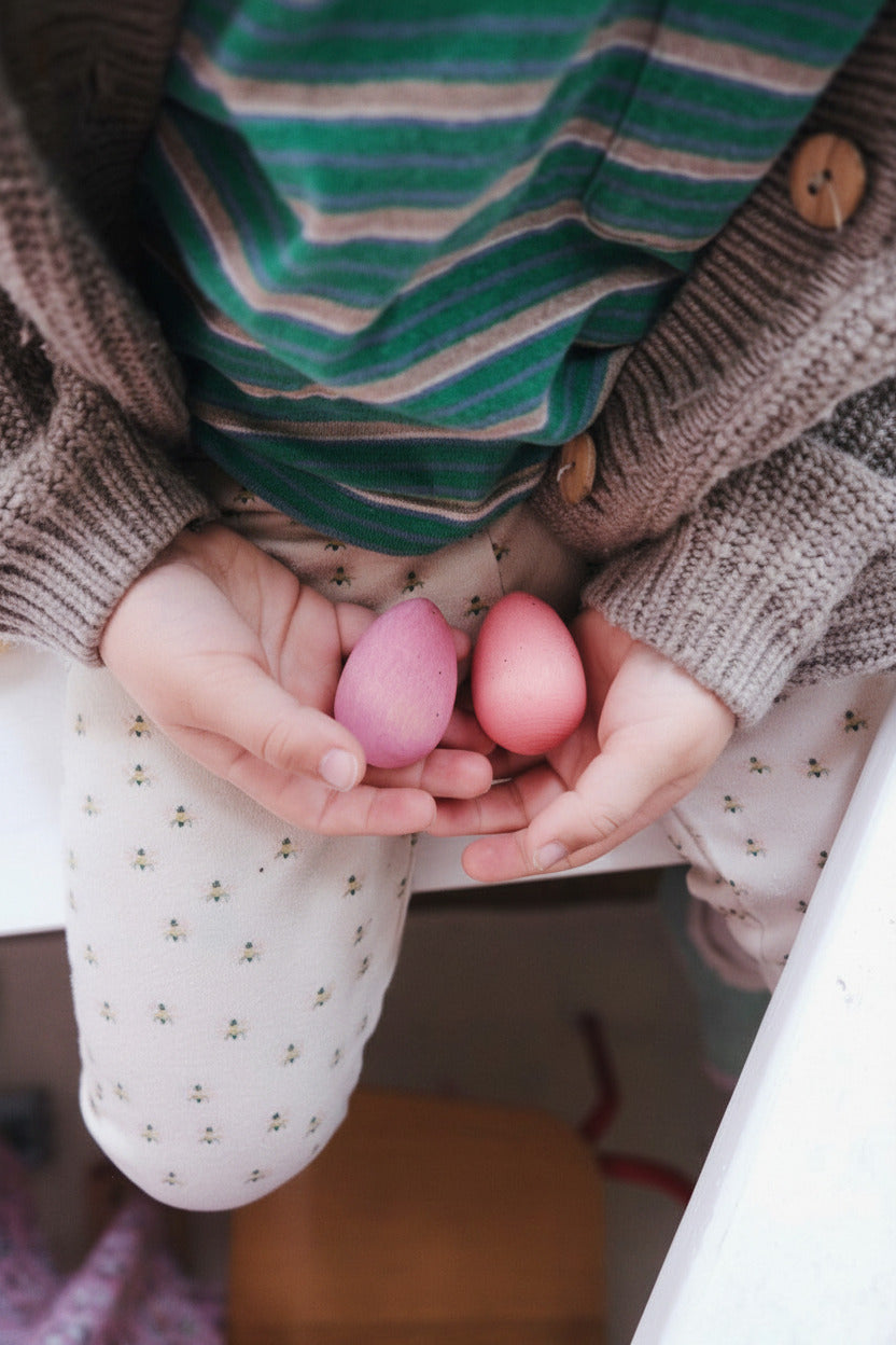Kind houdt drie pastelgekleurde Happy Eggs in beide handen