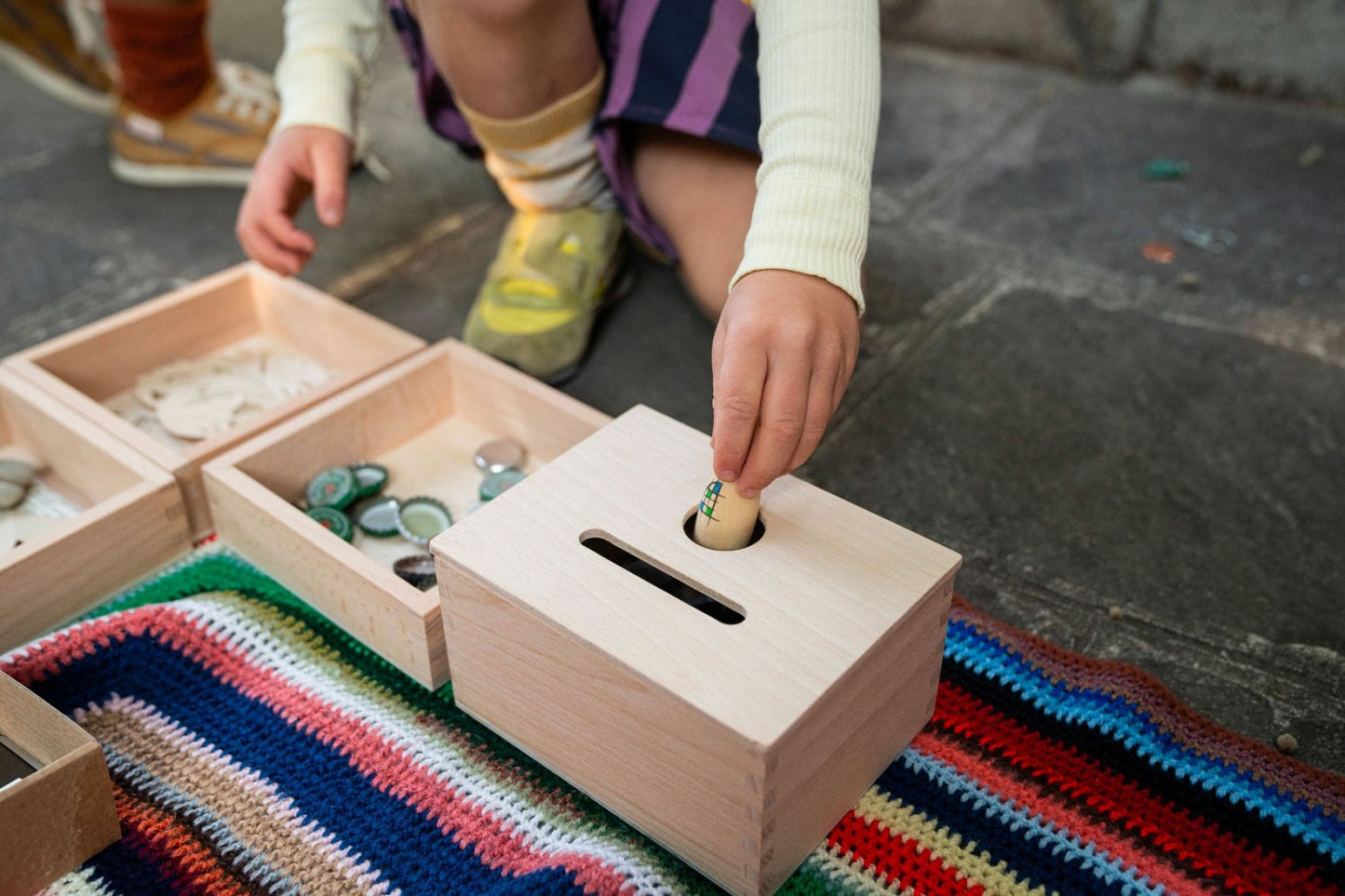 Kind stopt een speelstuk door de ronde opening van de Permanence Box
