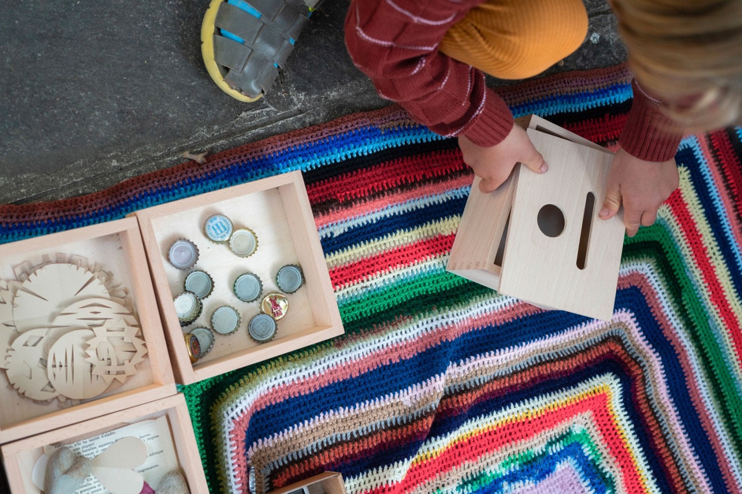 Kind steekt een houten munt door de gleuf van de Permanence Box