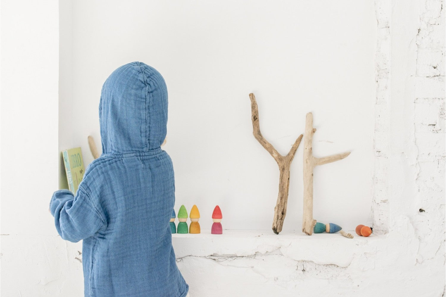 Kind zet Rainbow Tomtens op een lage witte plank