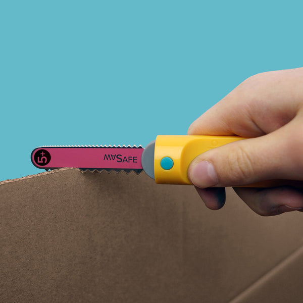 Hand zaagt met Makedo Safe-Saw langs de rand van karton