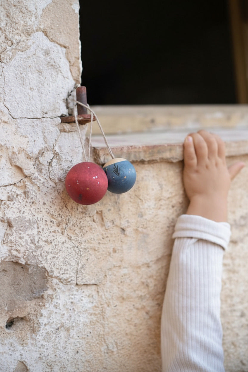 Kind hangt gekleurde Wish Balls aan een tak